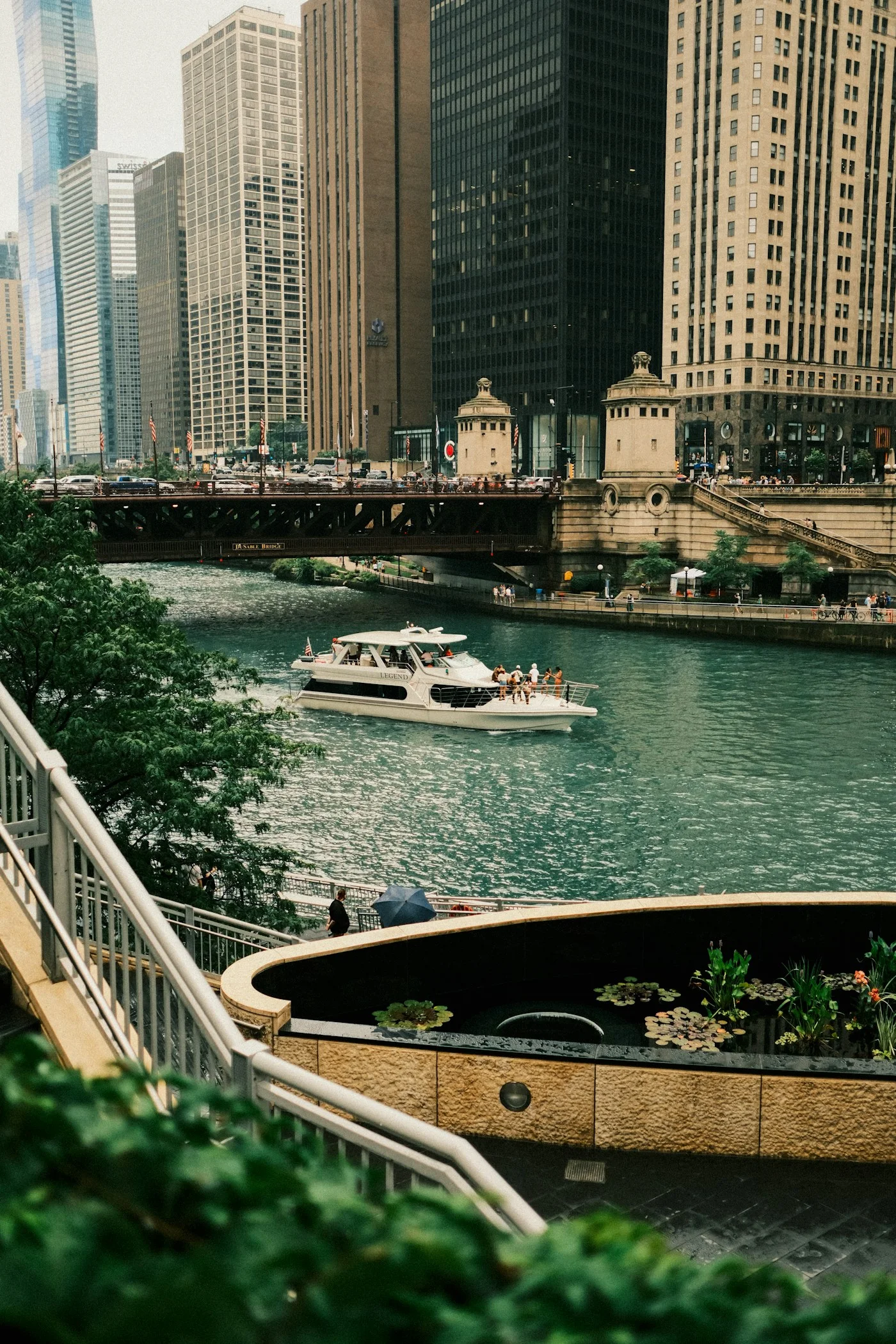 A small boat passing riverside steps and downtown Chicago buildings