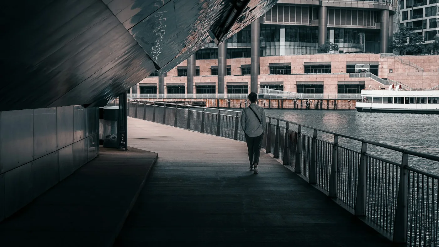 A person walking beside the Chicago River beneath a bridge
