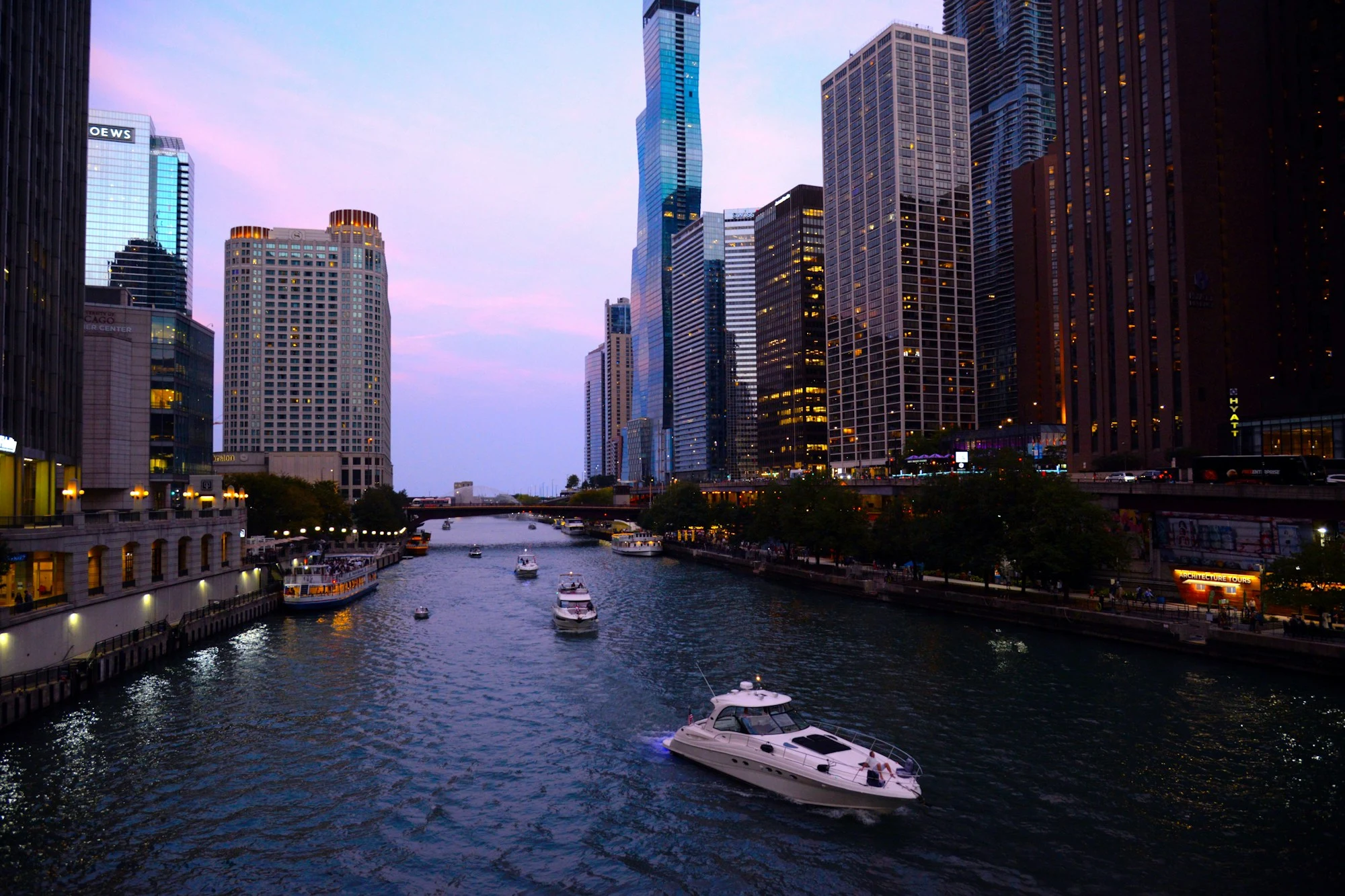 Boats on the Chicago River between downtown towers in evening light