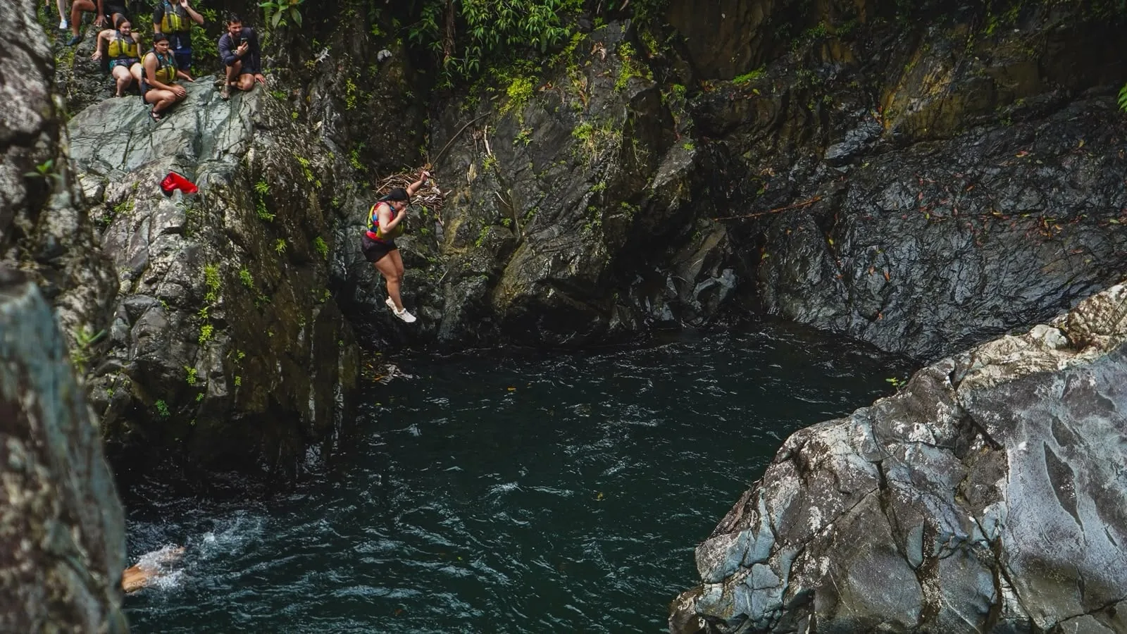 A participant above a rocky river pool